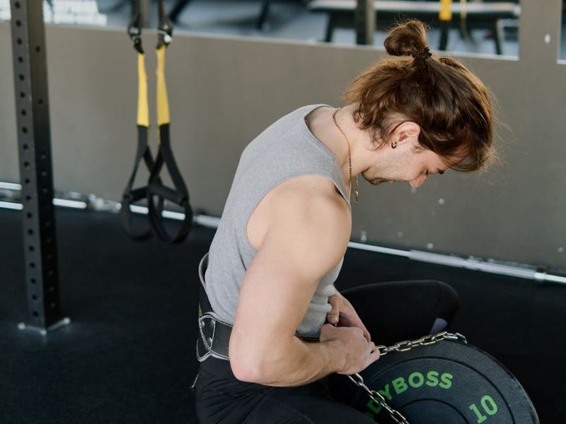 Athletic man performing a heavy lift in a dark room.